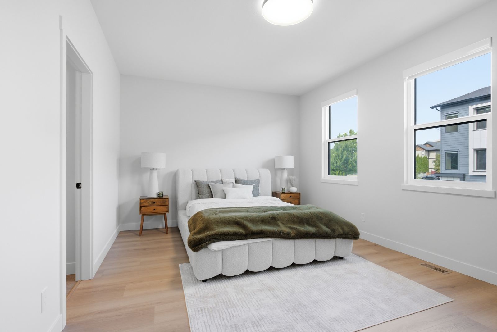 Show home bedroom with an upholstered bed and corner windows