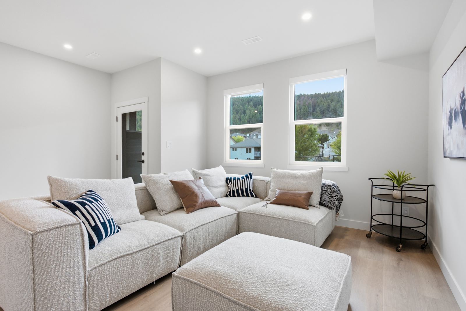 Show home family room with a sectional sofa and two windows